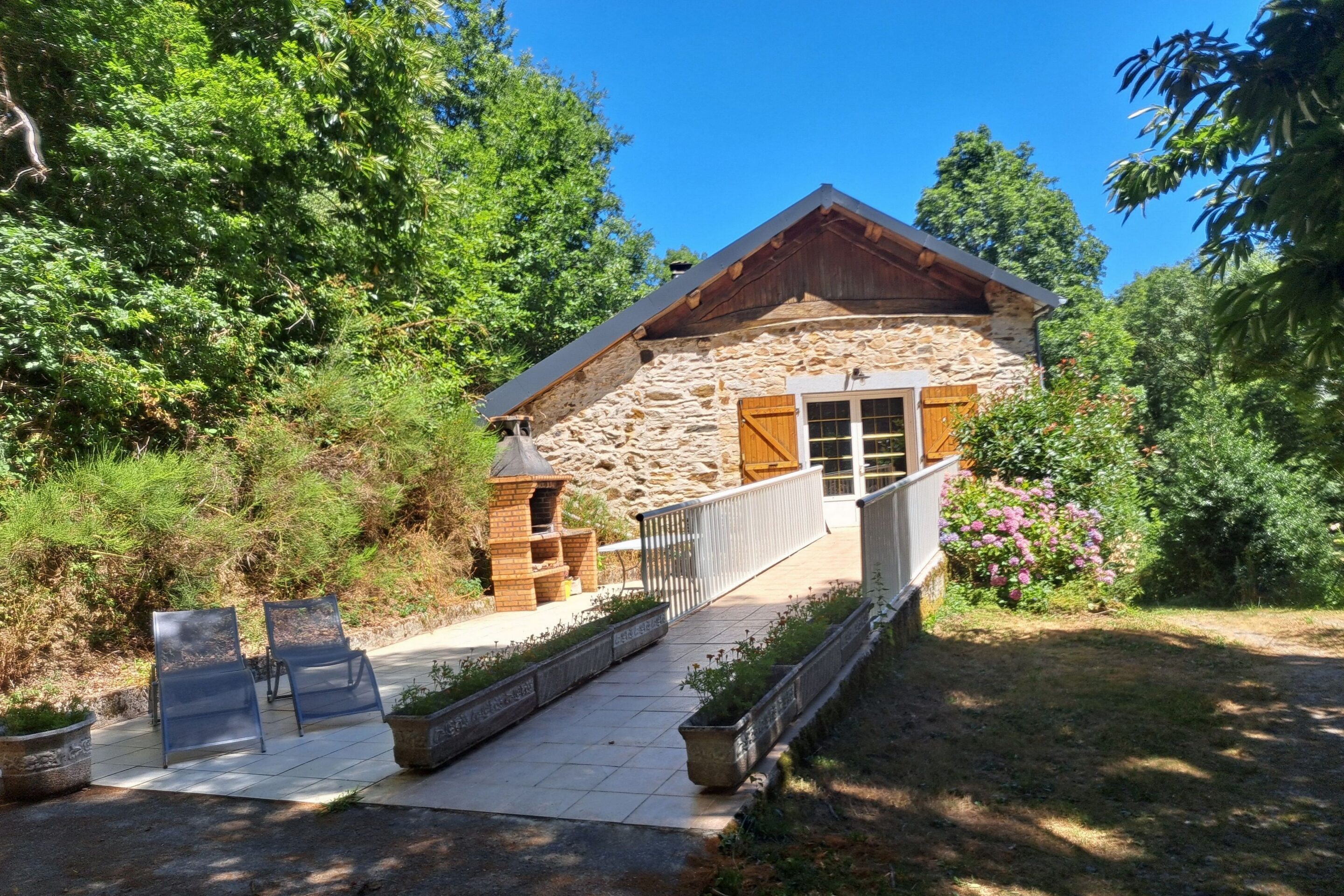Façade du gîte La Fénial, gîte dog-friendly dans le Tarn, entouré de verdure avec terrasse et barbecue pour des vacances en pleine nature.